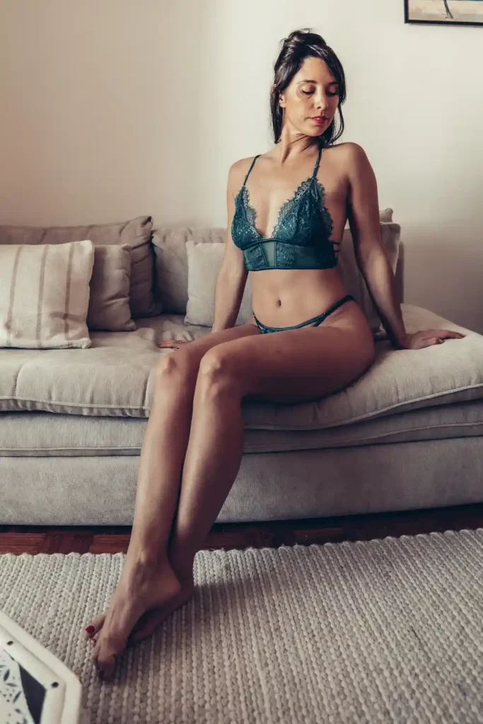 Lingerie verte Undiz portée par Caroline, assise sur un canapé beige, ambiance élégante et décontractée.