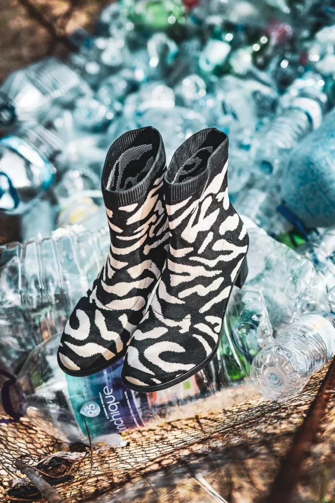 Paire de bottines à motif zébré posée sur un amas de bouteilles plastiques vides, en extérieur à Tavira dans l'Algarve en février 2025.